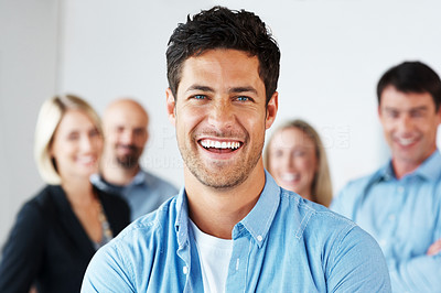 Confident young man smiling with people in background
