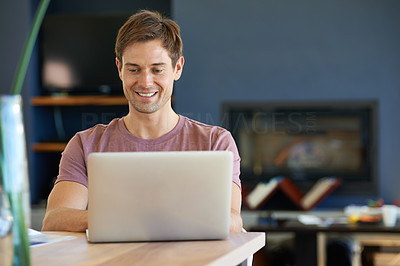 Cropped shot of a handsome young man sitting at a table using a laptop
