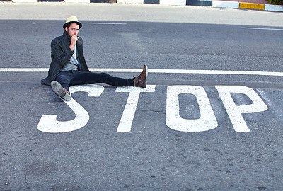 Shot of a handsome hipster sitting in the middle of the street