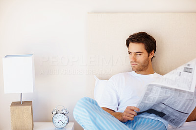 Thoughtful man reading a newspaper in bed