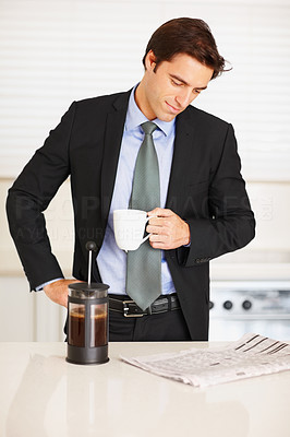 Young man reading newspaper while drinking coffee at home