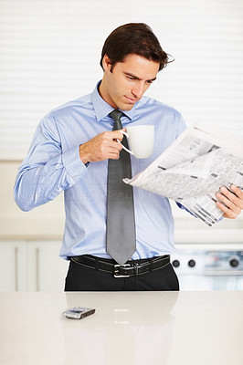 Young man drinking coffee while reading a financial newspaper