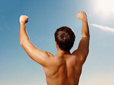 Rear view of a young guy with his hands raised towards the sky