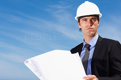 Successful architect holding a blueprint against clear sky