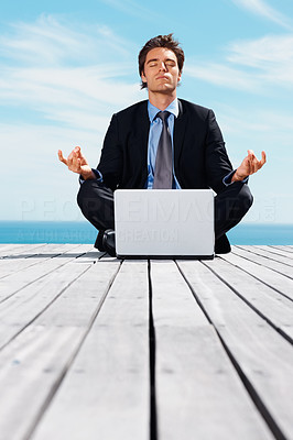 Relaxed business man in lotus position with laptop on a pier
