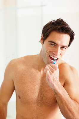 Portrait of a handsome young man brushing his teeth