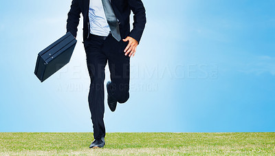 Male business executive running with a briefcase on a field