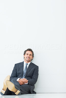 Smart smiling executive sitting against wall
