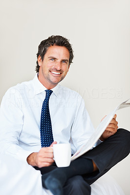 Man sitting on bed with coffee and newspaper