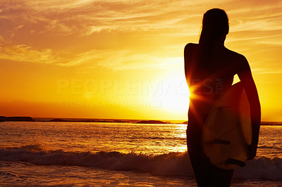 Woman carrying surfboard against sea at sunset - Silhouette