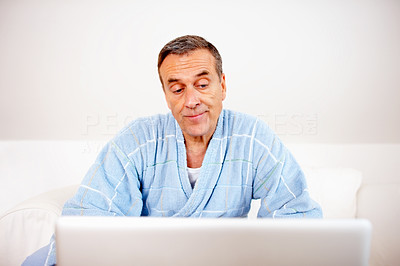 Happy senior man reading information from laptop against while