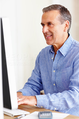 Smiling mature man calculating expenses using computer