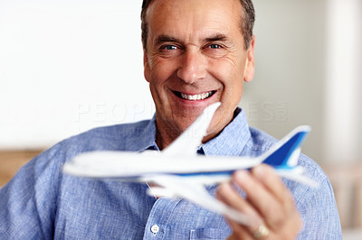 Happy pensioner playing with toy plane as he plans for vacation