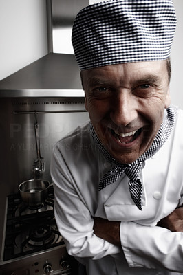Funny mature chef standing in front of gas stove and vent hood