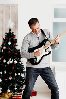 Joyful mature man playing guitar during Christmas