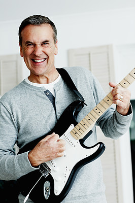 Cheerful mature man playing an acoustic guitar