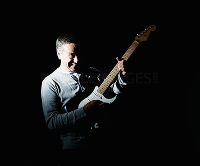 Cheerful mature man playing guitar against black background