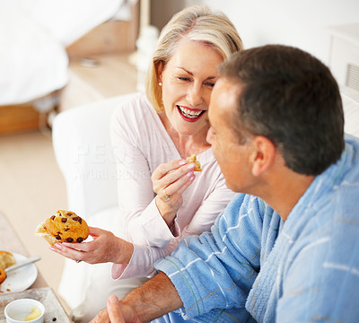 Cheerful mature woman feeding Muffin to husband