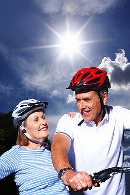 Mature couple with bicycle and protective helmet on a sunny day