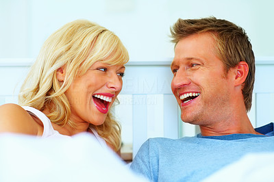 Cheerful middle aged couple laughing while looking at each other