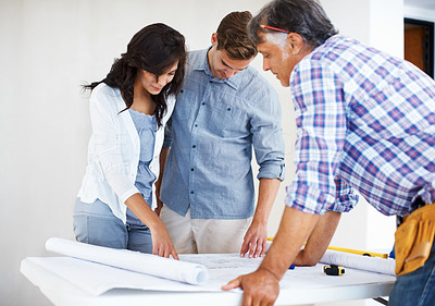 Young couple discussing house plan with architect