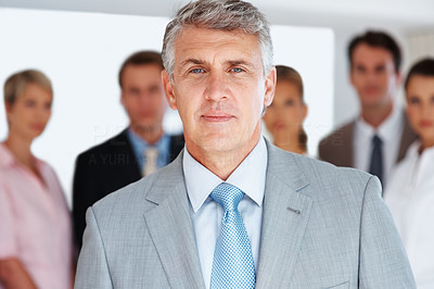 Confident male entrepreneur standing with colleagues in background