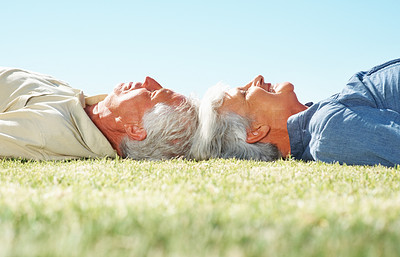 Senior couple lying on grass with heads together