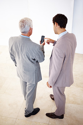 Two business men sharing information on cell phone