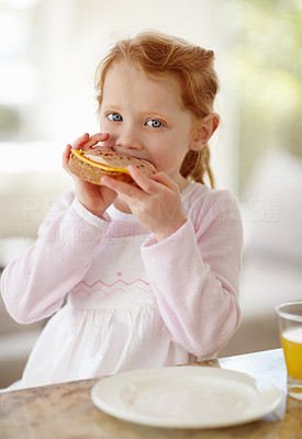 Happy adorable little girl eating sandwich for her breakfast