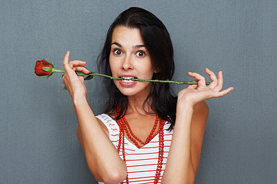 Playful woman posing with rose between teeth
