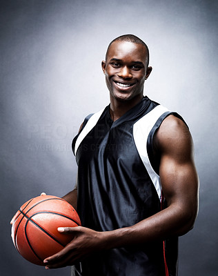 Muscular young basketball player smiling against dark background