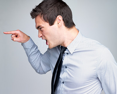 Angry young business man screaming and pointing