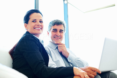 Happy relaxed mature business couple with laptop
