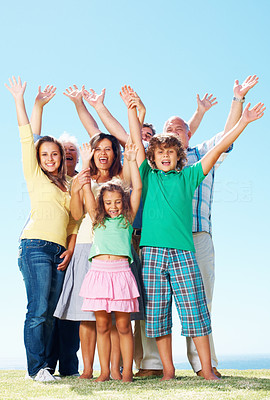 Family raising hands outdoors against clear blue sky
