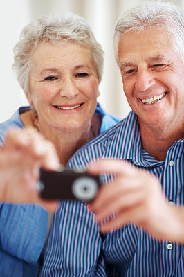 Smiling old couple taking a photo on mobile phone