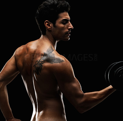 Trendy bodybuilder with tattoo lifts dumbbells against black