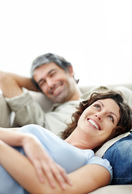Mature couple resting on couch smiling - Copyspace