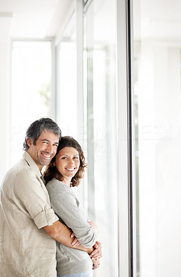 Happy mature couple embracing near a window