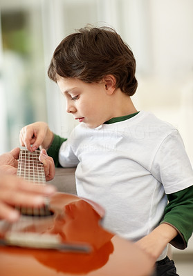 Sweet little boy learning to play acoustic guitar