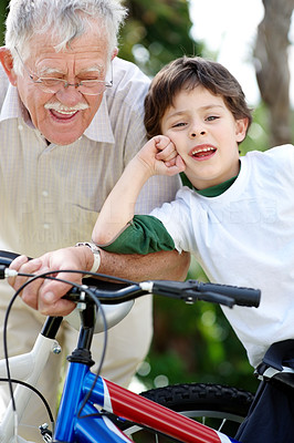 Happy young boy and his grandfather standing with bicycle