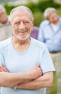 Retired old man smiling outdoors with hand folded