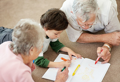 Old couple helping their grandson in making a drawing