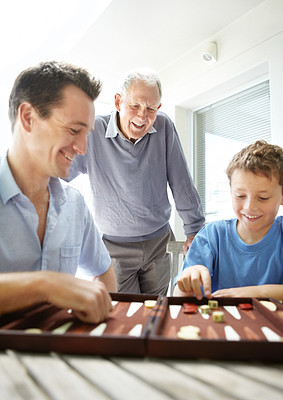 Little boy enjoys a game of backgammon with his father