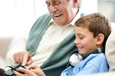 Smiling old man sitting with his grandson holding a mp3 player