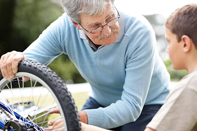 Old man repairing his grandson\'s bicycle