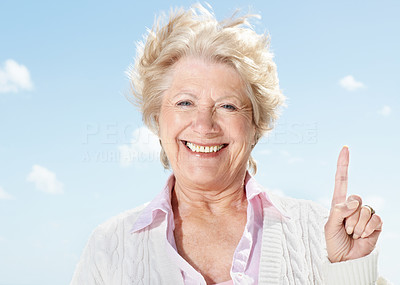Portrait of a smiling old woman pointing upwards