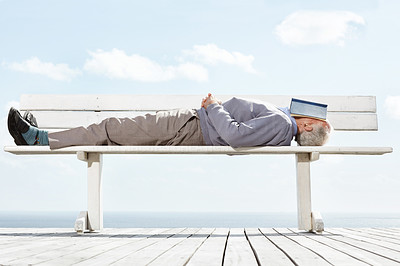 Old man sleeping on the bench with book on his face
