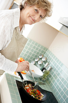 Happy old woman cooking in the kitchen - Indoor
