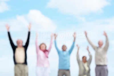 Group of senior friends with hand raised against the sky