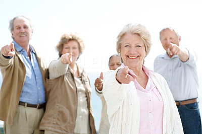Happy old woman pointing at you with her friends at back